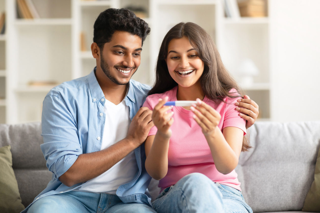 Couple souriant célébrant un test de grossesse positif, symbole d’espoir et de joie après un traitement de fertilité.